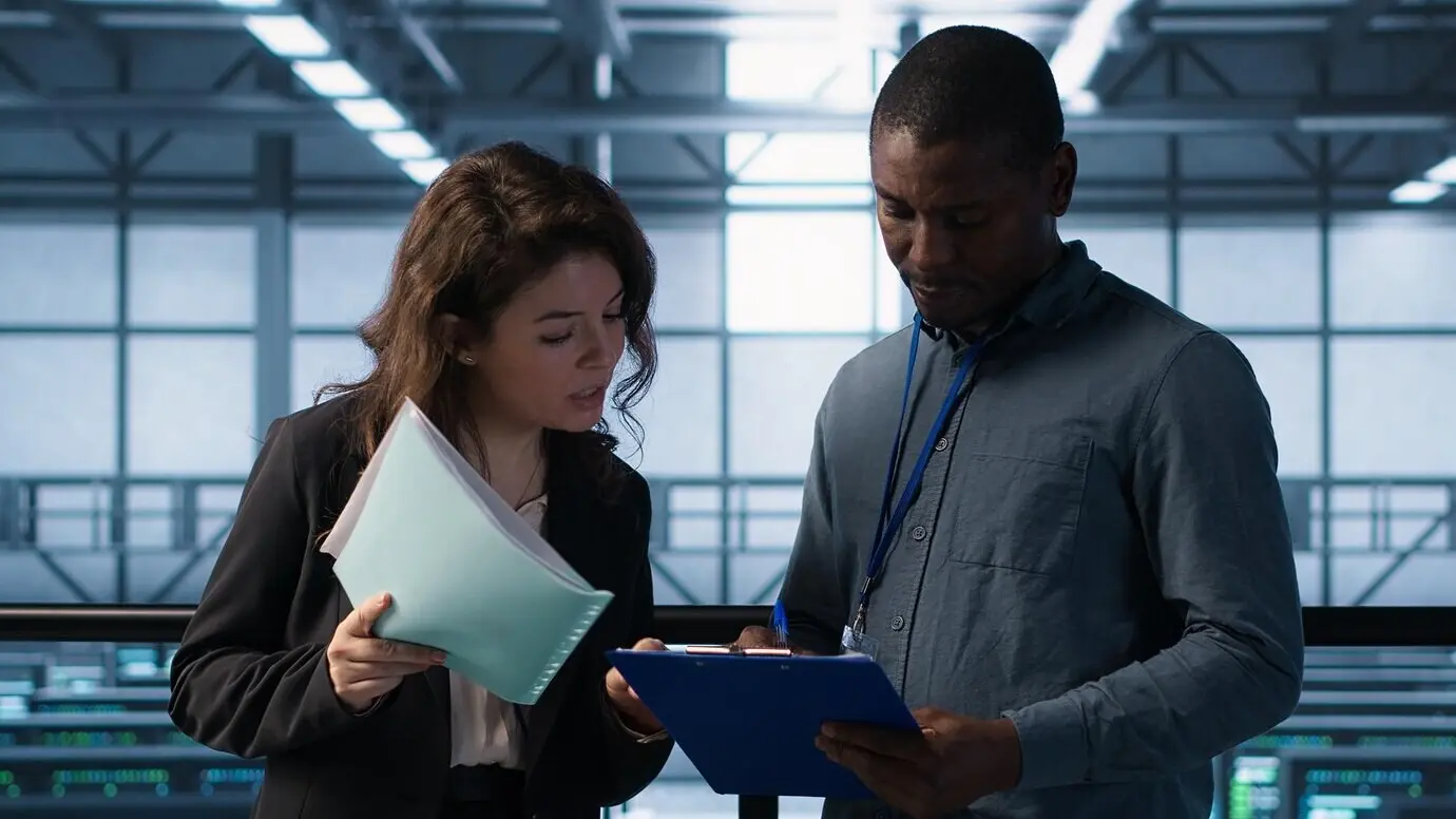 Руководители, управляющие центром обработки данных, читают бумажные документы.