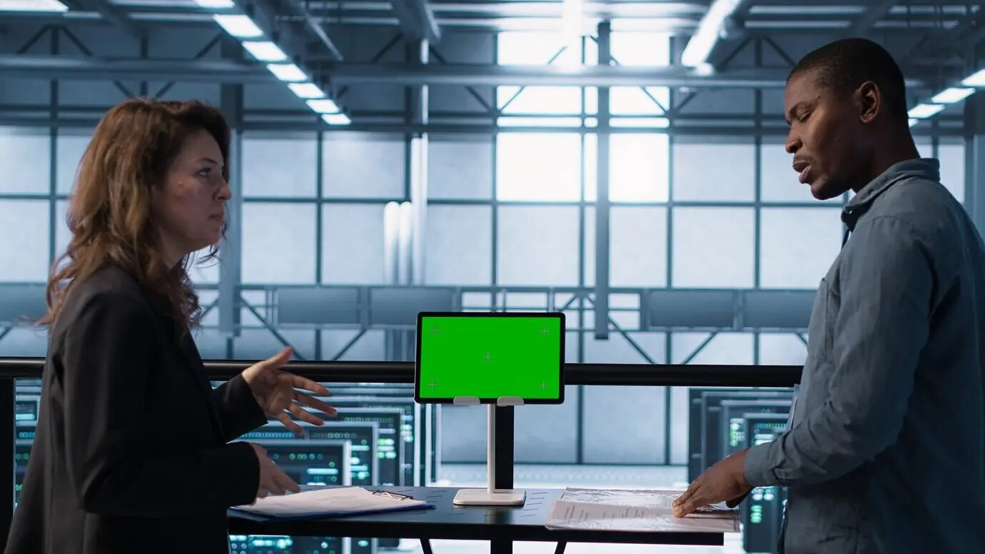 Команда дата-центра, используя макет планшета с зелёным экраном, изучает документацию.